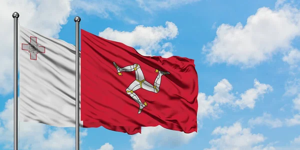 Malta und die Insel der Menschen schwenken gemeinsam die Flagge im Wind gegen den wolkenverhangenen blauen Himmel. Diplomatie-Konzept, internationale Beziehungen. — Stockfoto