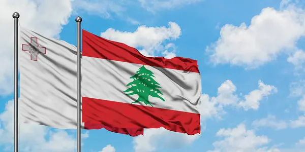 Bandera de Malta y Líbano ondeando en el viento contra el cielo azul nublado blanco juntos. Concepto diplomático, relaciones internacionales . — Foto de Stock