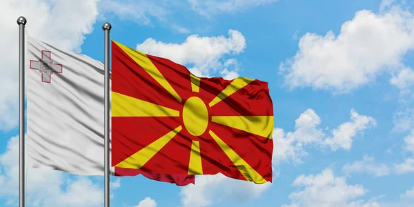 Bandera de Malta y Macedonia ondeando en el viento contra el cielo azul nublado blanco juntos. Concepto diplomático, relaciones internacionales . — Foto de Stock