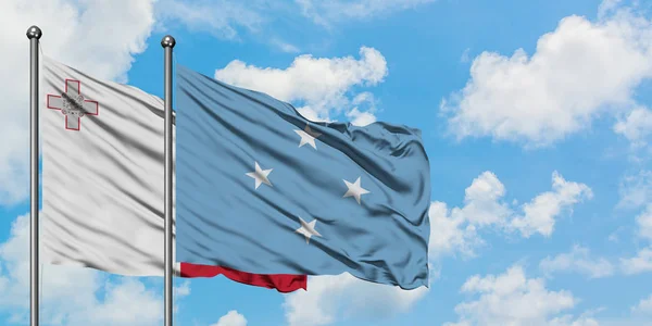 Bandera de Malta y Micronesia ondeando en el viento contra el cielo azul nublado blanco juntos. Concepto diplomático, relaciones internacionales . — Foto de Stock