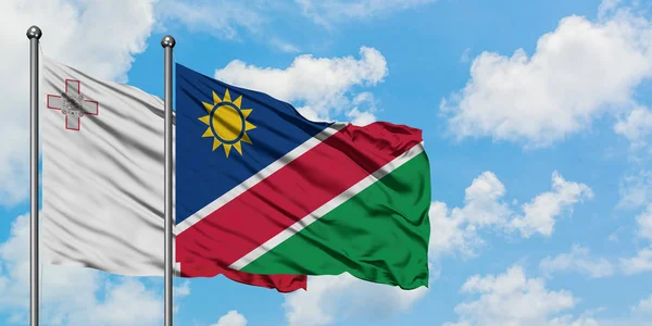 Malta en Namibië vlag zwaaien in de wind tegen witte bewolkte blauwe hemel samen. Diplomatie concept, internationale betrekkingen. — Stockfoto