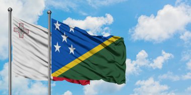 Malta ve Solomon Adaları bayrağı birlikte beyaz bulutlu mavi gökyüzüne karşı rüzgarda sallayarak. Diplomasi kavramı, uluslararası ilişkiler.