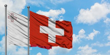 Malta ve İsviçre bayrağı birlikte beyaz bulutlu mavi gökyüzüne karşı rüzgarsal sallayarak. Diplomasi kavramı, uluslararası ilişkiler.