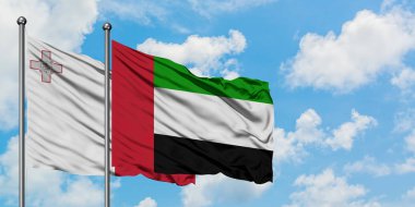 Malta ve Birleşik Arap Emirlikleri bayrağı birlikte beyaz bulutlu mavi gökyüzüne karşı rüzgarsal sallayarak. Diplomasi kavramı, uluslararası ilişkiler.