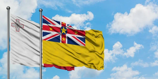 Bandera de Malta y Niue ondeando en el viento contra el cielo azul nublado blanco juntos. Concepto diplomático, relaciones internacionales . — Foto de Stock