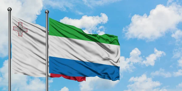 Bandera de Malta y Sierra Leona ondeando en el viento contra el cielo azul nublado blanco juntos. Concepto diplomático, relaciones internacionales . — Foto de Stock