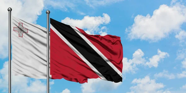Malta en Trinidad en Tobago vlag zwaaien in de wind tegen witte bewolkte blauwe hemel samen. Diplomatie concept, internationale betrekkingen. — Stockfoto