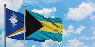 Marshall Adaları ve Bahamalar bayrağı birlikte beyaz bulutlu mavi gökyüzüne karşı rüzgarda sallayarak. Diplomasi kavramı, uluslararası ilişkiler.