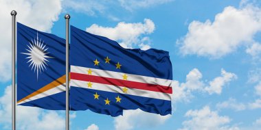 Marshall Adaları ve Cape Verde bayrağı birlikte beyaz bulutlu mavi gökyüzüne karşı rüzgarda sallayarak. Diplomasi kavramı, uluslararası ilişkiler.