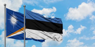 Marshall Adaları ve Estonya bayrağı birlikte beyaz bulutlu mavi gökyüzüne karşı rüzgarda sallayarak. Diplomasi kavramı, uluslararası ilişkiler.