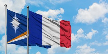 Marshall Adaları ve Fransa bayrağı birlikte beyaz bulutlu mavi gökyüzüne karşı rüzgarda sallayarak. Diplomasi kavramı, uluslararası ilişkiler.