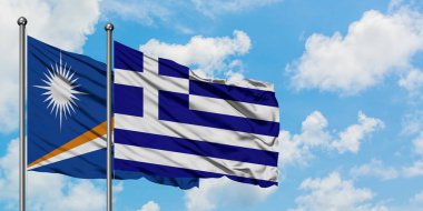 Marshall Adaları ve Yunanistan bayrağı birlikte beyaz bulutlu mavi gökyüzüne karşı rüzgarda sallayarak. Diplomasi kavramı, uluslararası ilişkiler.