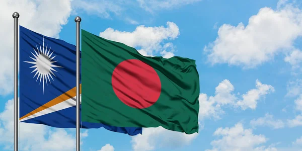Bandera de las Islas Marshall y Bangladesh ondeando en el viento contra el cielo azul nublado blanco juntos. Concepto diplomático, relaciones internacionales . — Foto de Stock