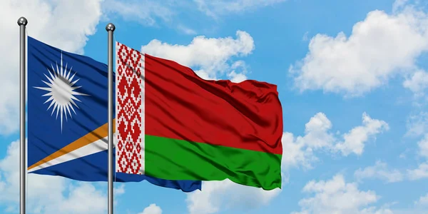 Bandera de las Islas Marshall y Bielorrusia ondeando en el viento contra el cielo azul nublado blanco juntos. Concepto diplomático, relaciones internacionales . — Foto de Stock