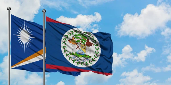 Marshall Adaları ve Belize bayrağı birlikte beyaz bulutlu mavi gökyüzüne karşı rüzgarda sallayarak. Diplomasi kavramı, uluslararası ilişkiler. — Stok fotoğraf