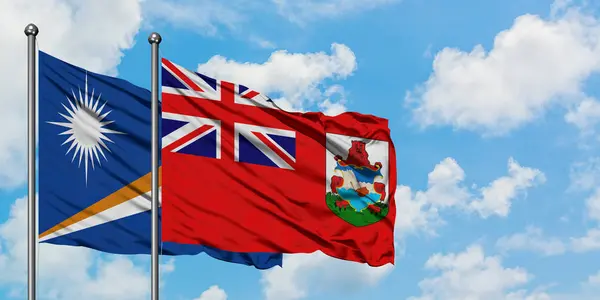 Bandera de las Islas Marshall y Bermudas ondeando en el viento contra el cielo azul nublado blanco juntos. Concepto diplomático, relaciones internacionales . —  Fotos de Stock