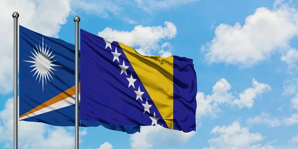 Η σημαία των Νήσων Μάρσαλ και της Βοσνίας Ερζεγοβίνης κυματίζει στον άνεμο ενάντια στον λευκό συννεφιασμένο γαλάζιο ουρανό. Φιλοσοφία της διπλωματίας, διεθνείς σχέσεις. — Φωτογραφία Αρχείου