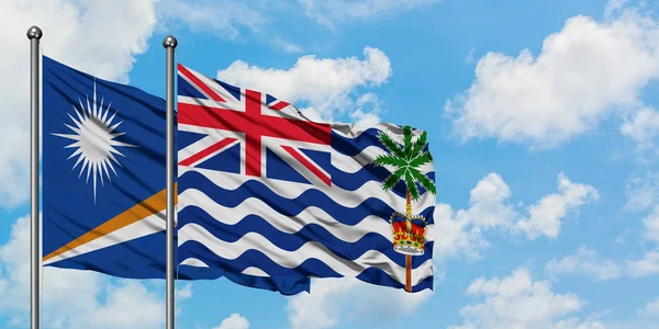 Bandera de las Islas Marshall y del Territorio Británico del Océano Índico ondeando en el viento contra el cielo azul nublado blanco juntos. Concepto diplomático, relaciones internacionales . — Foto de Stock