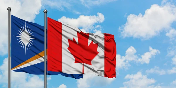 Isole Marshall e la bandiera del Canada sventolano nel vento contro il bianco cielo blu nuvoloso insieme. Concetto di diplomazia, relazioni internazionali . — Foto Stock