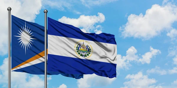 Bandera de las Islas Marshall y El Salvador ondeando en el viento contra el cielo azul nublado blanco juntos. Concepto diplomático, relaciones internacionales . — Foto de Stock
