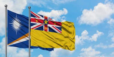 Marshall Adaları ve Niue bayrağı birlikte beyaz bulutlu mavi gökyüzüne karşı rüzgarda sallayarak. Diplomasi kavramı, uluslararası ilişkiler.