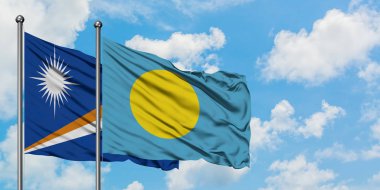 Marshall Adaları ve Palau bayrağı birlikte beyaz bulutlu mavi gökyüzüne karşı rüzgarda sallayarak. Diplomasi kavramı, uluslararası ilişkiler.