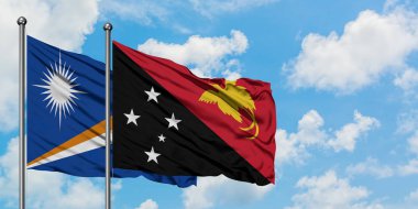 Marshall Adaları ve Papua Yeni Gine bayrağı birlikte beyaz bulutlu mavi gökyüzüne karşı rüzgarda sallayarak. Diplomasi kavramı, uluslararası ilişkiler.