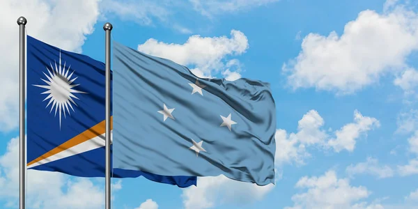 Ilhas Marshall e a bandeira da Micronésia agitando no vento contra o céu azul nublado branco juntos. Conceito de diplomacia, relações internacionais . — Fotografia de Stock