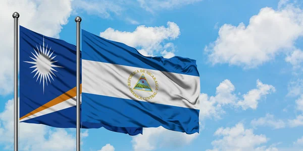 Wyspy Marshalla i Nikaragua flagi machając w wiatr przed białym zachmurzone błękitne niebo razem. Koncepcja dyplomacji, stosunki międzynarodowe. — Zdjęcie stockowe