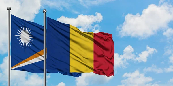 Bandera de las Islas Marshall y Rumania ondeando en el viento contra el cielo azul nublado blanco juntos. Concepto diplomático, relaciones internacionales . — Foto de Stock
