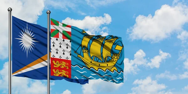 马绍尔群岛和圣皮埃尔和密克隆国旗在风中飘扬，与白云相间的蓝天相一起。外交概念、国际关系. — 图库照片