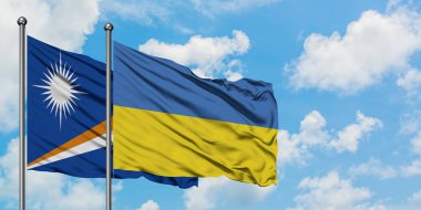 Marshall Adaları ve Ukrayna bayrağı birlikte beyaz bulutlu mavi gökyüzüne karşı rüzgarda sallayarak. Diplomasi kavramı, uluslararası ilişkiler.