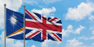 Marshall Adaları ve Birleşik Krallık bayrağı birlikte beyaz bulutlu mavi gökyüzüne karşı rüzgarda sallayarak. Diplomasi kavramı, uluslararası ilişkiler.