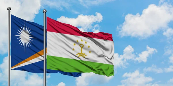Bandera de las Islas Marshall y Tayikistán ondeando en el viento contra el cielo azul nublado blanco juntos. Concepto diplomático, relaciones internacionales . — Foto de Stock