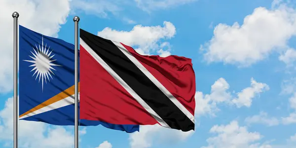 Marshall Adaları ve Trinidad ve Tobago bayrağı birlikte beyaz bulutlu mavi gökyüzüne karşı rüzgarda sallayarak. Diplomasi kavramı, uluslararası ilişkiler. — Stok fotoğraf
