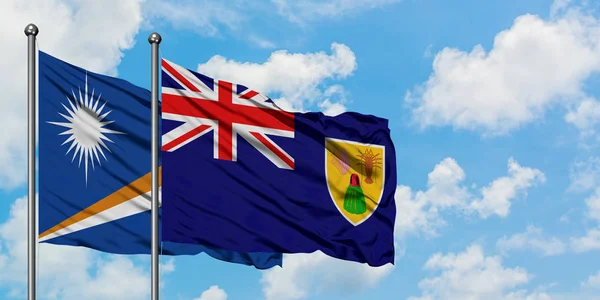 Marshall eilanden en Turks-en Caicoseilanden vlag zwaaien in de wind tegen witte bewolkte blauwe hemel samen. Diplomatie concept, internationale betrekkingen. — Stockfoto