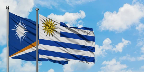 Bandera de las Islas Marshall y Uruguay ondeando en el viento contra el cielo azul nublado blanco juntos. Concepto diplomático, relaciones internacionales . —  Fotos de Stock