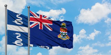 Martinik ve Cayman Adaları bayrağı birlikte beyaz bulutlu mavi gökyüzüne karşı rüzgarda sallayarak. Diplomasi kavramı, uluslararası ilişkiler.