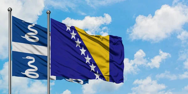 Martinica e Bósnia-Herzegovina acenando com o vento contra o céu azul nublado branco juntos. Conceito de diplomacia, relações internacionais . — Fotografia de Stock