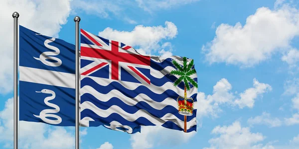 Bandera de Martinica y del Territorio Británico del Océano Índico ondeando en el viento contra el cielo azul nublado blanco juntos. Concepto diplomático, relaciones internacionales . — Foto de Stock