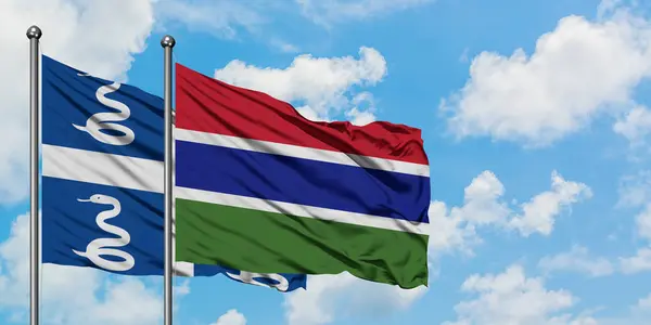 Bandera de Martinica y Gambia ondeando en el viento contra el cielo azul nublado blanco juntos. Concepto diplomático, relaciones internacionales . — Foto de Stock