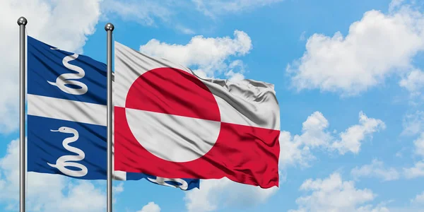 Martinica y bandera de Groenlandia ondeando en el viento contra el cielo azul nublado blanco juntos. Concepto diplomático, relaciones internacionales . —  Fotos de Stock