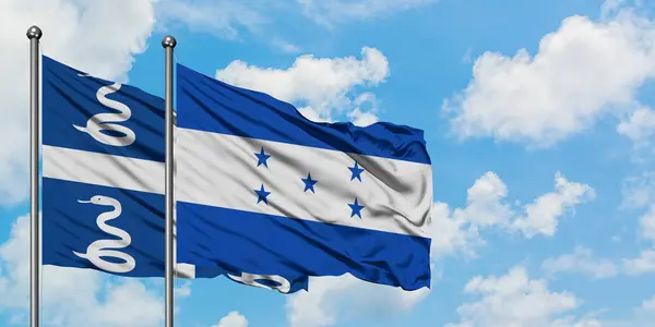 Martinik ve Honduras bayrağı birlikte beyaz bulutlu mavi gökyüzüne karşı rüzgarda sallayarak. Diplomasi kavramı, uluslararası ilişkiler. — Stok fotoğraf