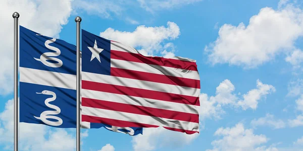 Martinik ve Liberya bayrağı birlikte beyaz bulutlu mavi gökyüzüne karşı rüzgarda sallayarak. Diplomasi kavramı, uluslararası ilişkiler. — Stok fotoğraf