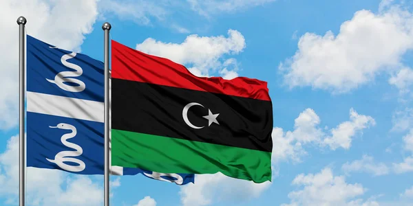 Bandera de Martinica y Libia ondeando en el viento contra el cielo azul nublado blanco juntos. Concepto diplomático, relaciones internacionales . — Foto de Stock