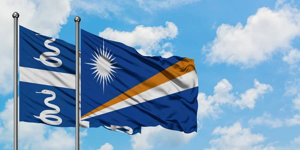A Martinica e as Ilhas Marshall acenam ao vento contra o céu azul nublado branco juntos. Conceito de diplomacia, relações internacionais . — Fotografia de Stock