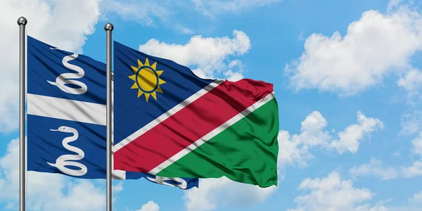 Bandera de Martinica y Namibia ondeando en el viento contra el cielo azul nublado blanco juntos. Concepto diplomático, relaciones internacionales . — Foto de Stock