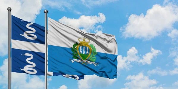Martinik ve San Marino bayrağı birlikte beyaz bulutlu mavi gökyüzüne karşı rüzgarda sallayarak. Diplomasi kavramı, uluslararası ilişkiler. — Stok fotoğraf