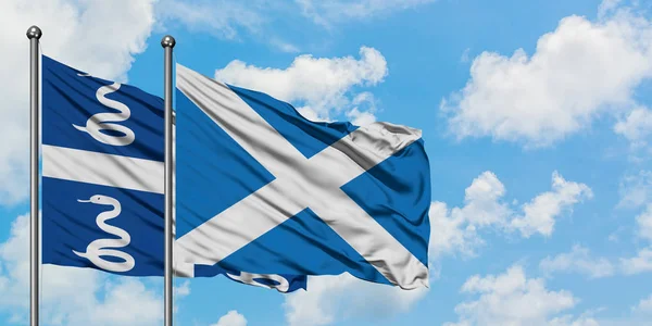 Martinica y la bandera de Escocia ondeando en el viento contra el cielo azul nublado blanco juntos. Concepto diplomático, relaciones internacionales . — Foto de Stock