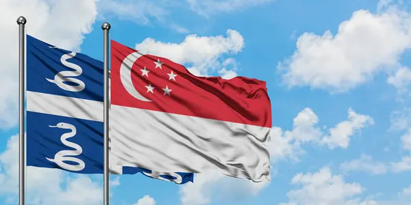 Martinik ve Singapur bayrağı birlikte beyaz bulutlu mavi gökyüzüne karşı rüzgarda sallayarak. Diplomasi kavramı, uluslararası ilişkiler. — Stok fotoğraf